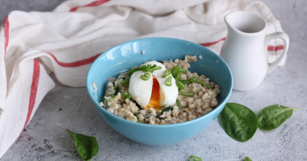тарелка соленой овсянки с яйцом пашот и свежей зеленью